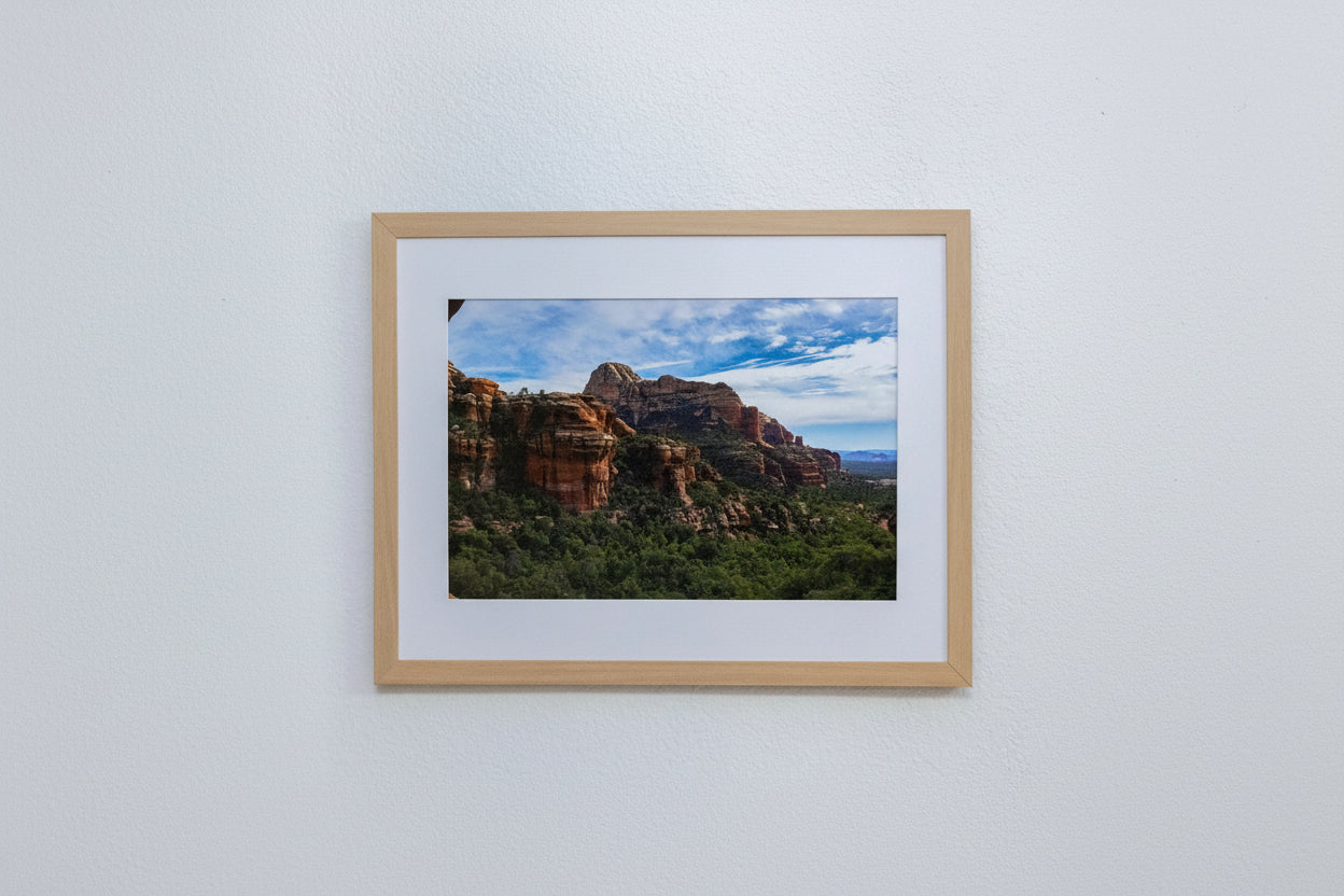 Framed photograph of a mountain landscape with a wooden frame on a white wall.