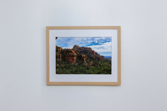 Framed photograph of a mountain landscape with a wooden frame on a white wall.